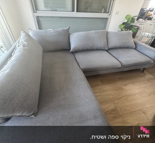 ספה אפורה בחדר עם רצפת עץ